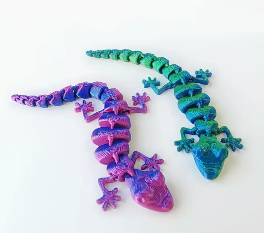 Two 3D-printed lizards, one blue and one purple, on a white background