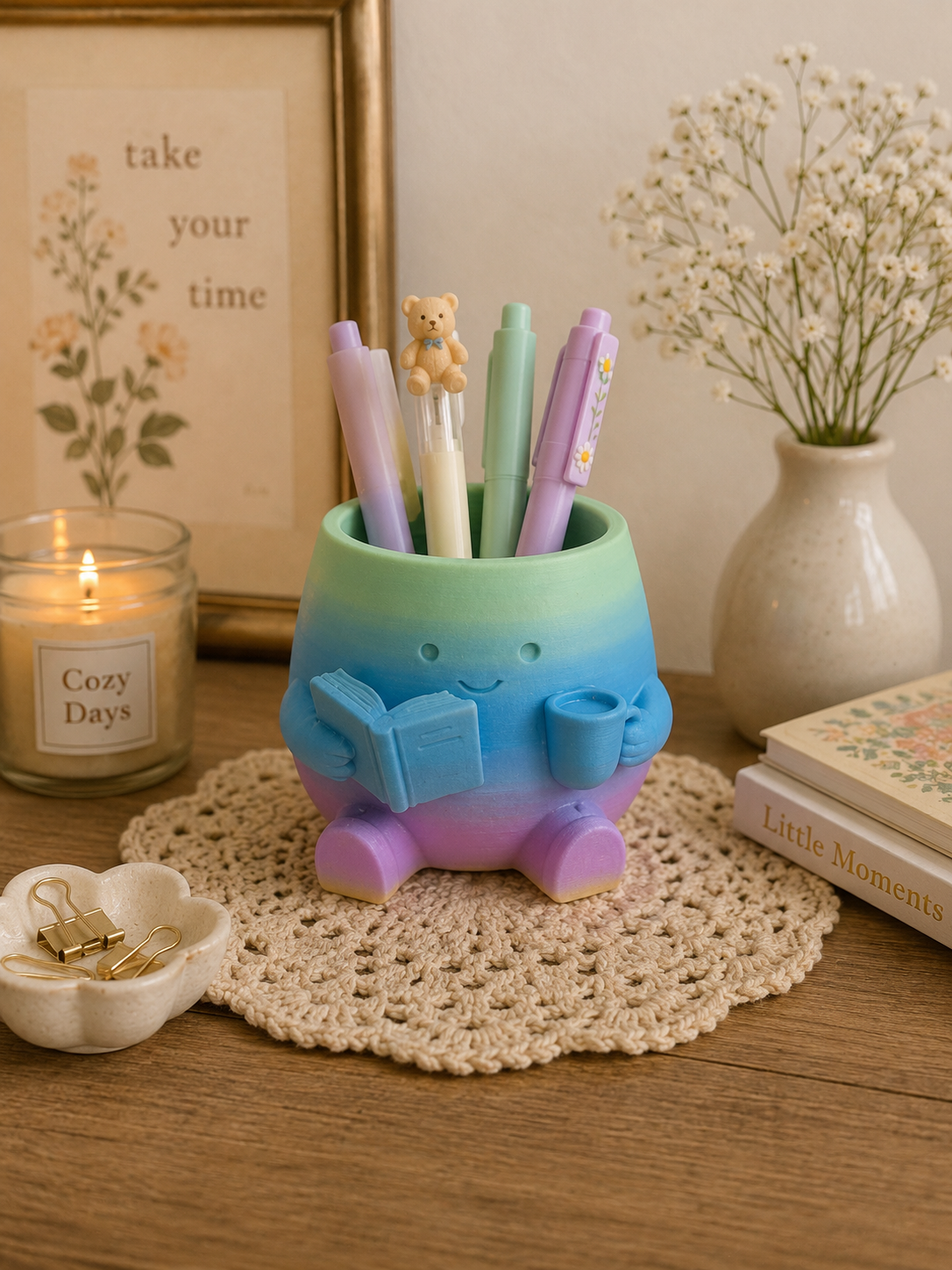 3D printed pastel rainbow pen holder with smiling reading character and coffee mug