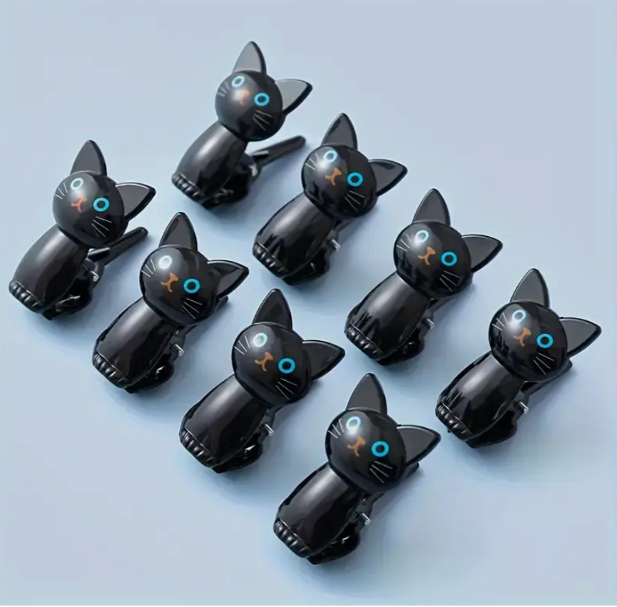 Black cat-shaped phone clips on a light blue background
