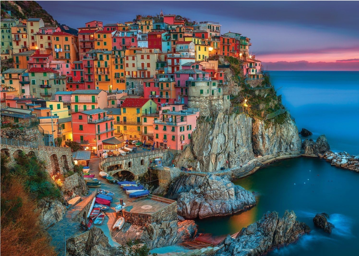 Colorful village perched on a cliff overlooking the ocean at dusk.