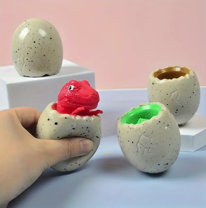 Hand holding a small red creature emerging from a speckled egg, with other speckled eggs on a light pink background.