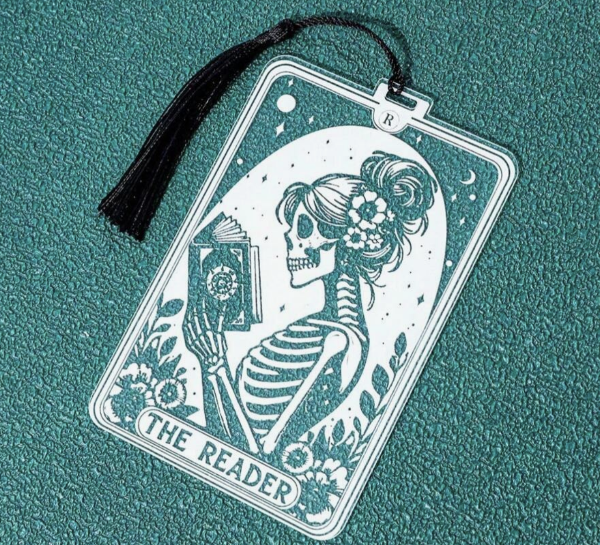 Decorative card with a skeleton holding a book titled 'The Reader' on a teal background