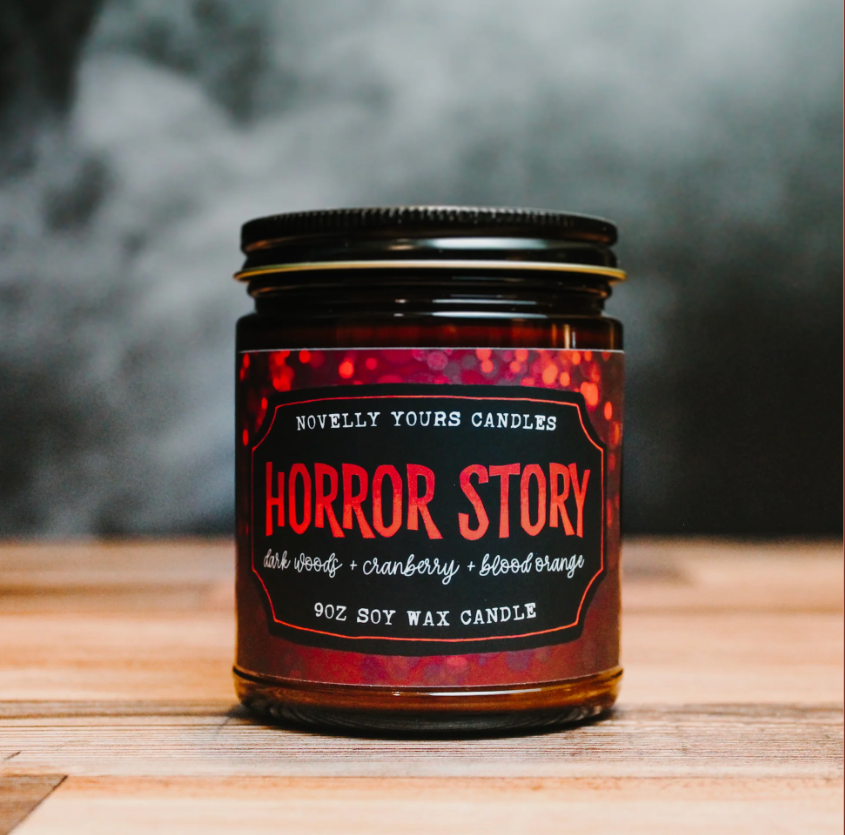 Candle jar labeled 'Horror Story' with a dark label on a wooden surface.