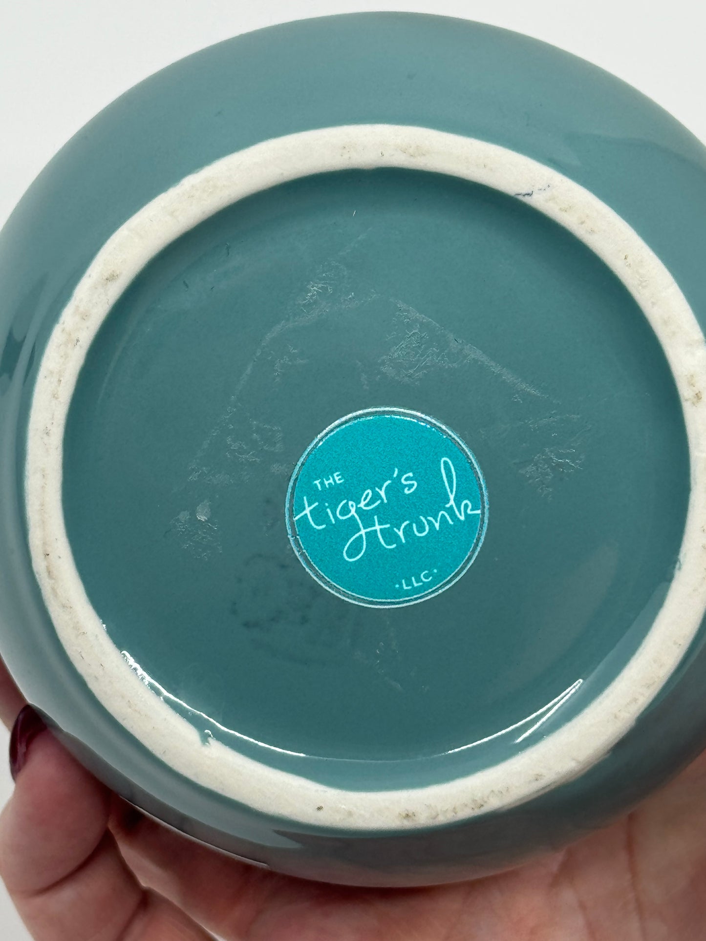 Teal ceramic product with 'The Tiger's Trunk' logo on a white background