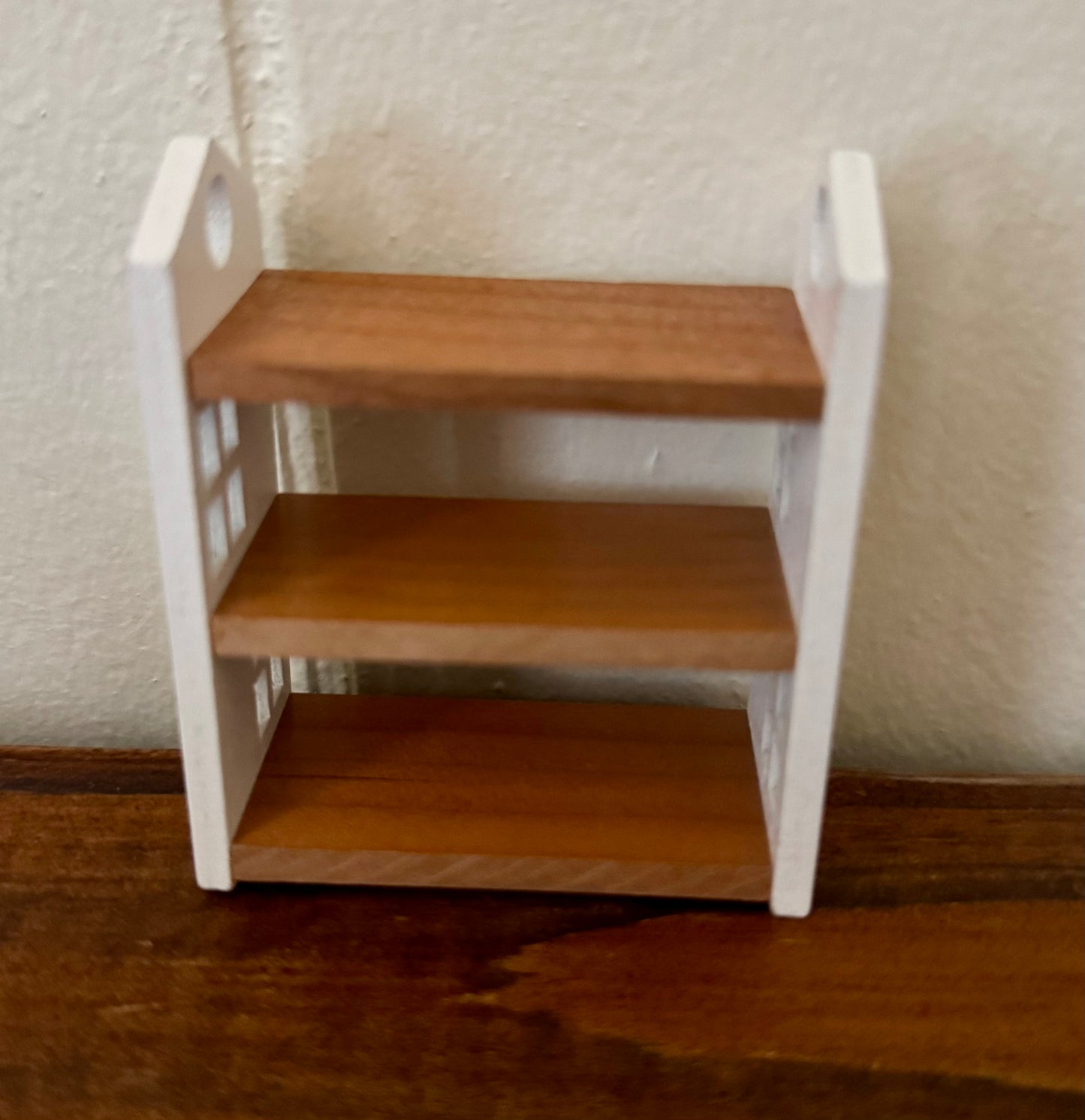 Small wooden shelf with three steps on a plain background