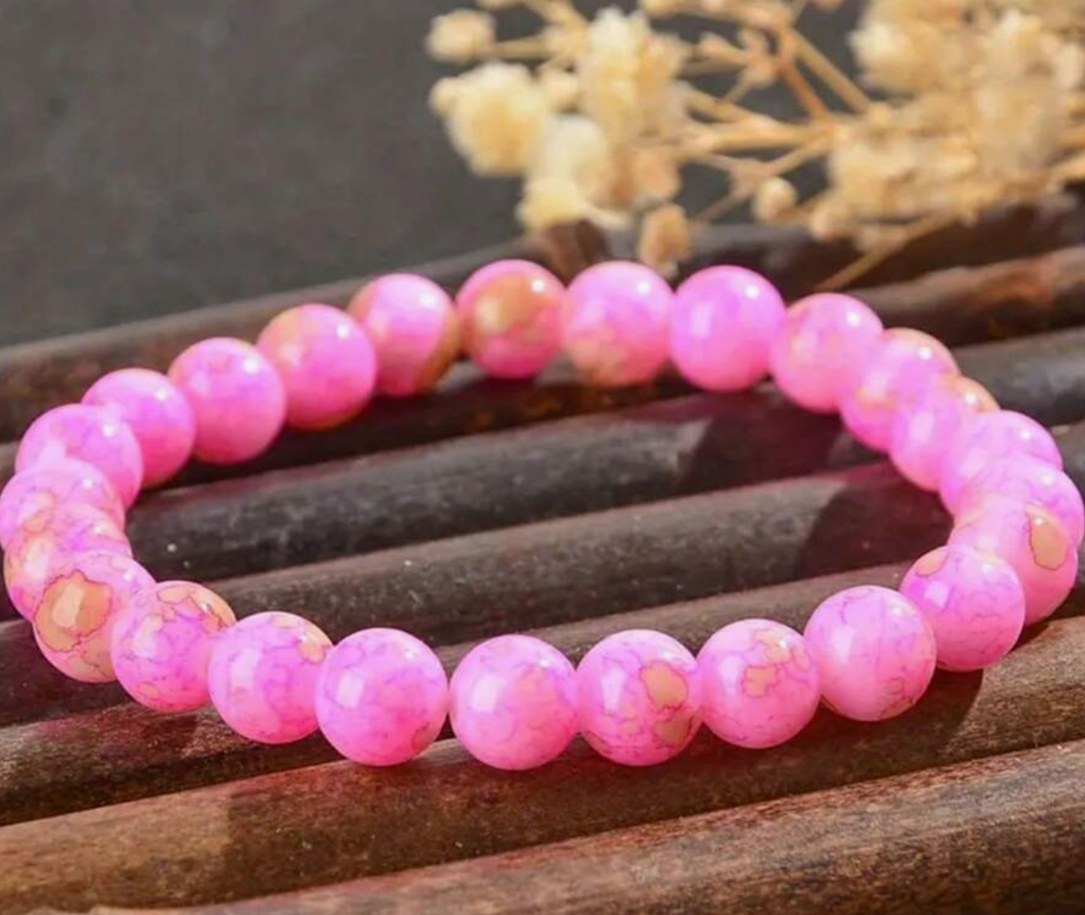 Pink beaded bracelet on a wooden surface with blurred background