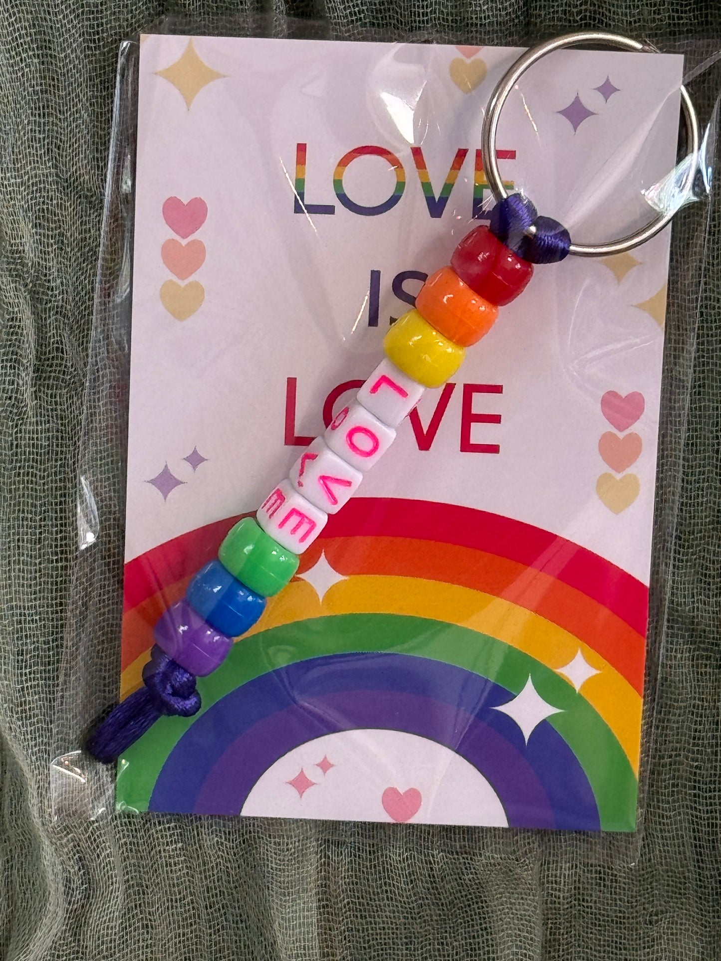 Beaded rainbow Pride keychain with word bead charms like Pride and Love on a Love is Love card