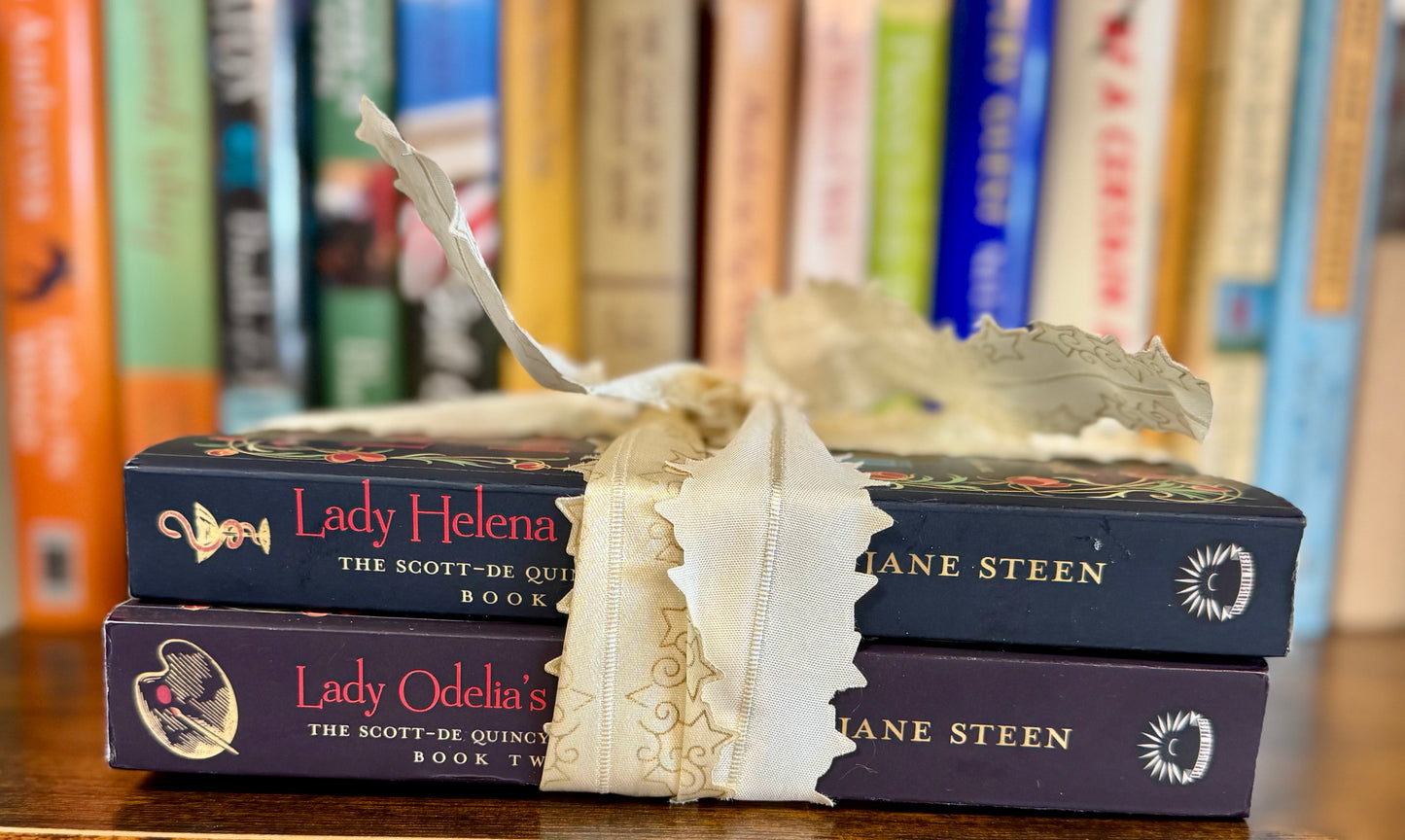Book bundle tied with ribbon featuring Lady Helena Investigates and Lady Odelia’s Secret, the first two books in the Scott-De Quincy Mysteries