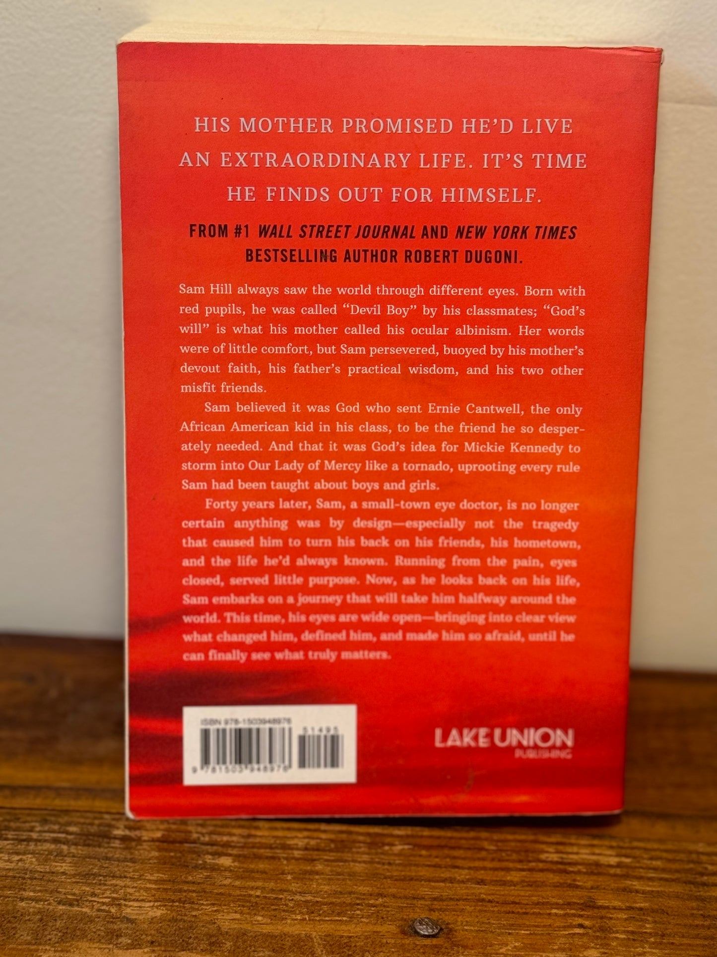 Cover of The Extraordinary Life of Sam Hell by Robert Dugoni, depicting a young boy with striking red eyes against a backdrop of a school setting.