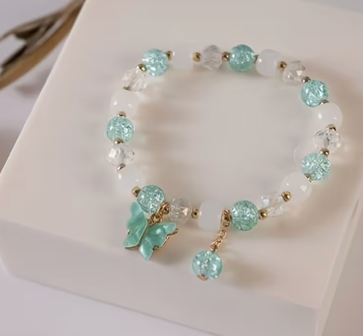 Aqua and white beaded bracelet with clear faceted beads gold tone accents and aqua butterfly charm