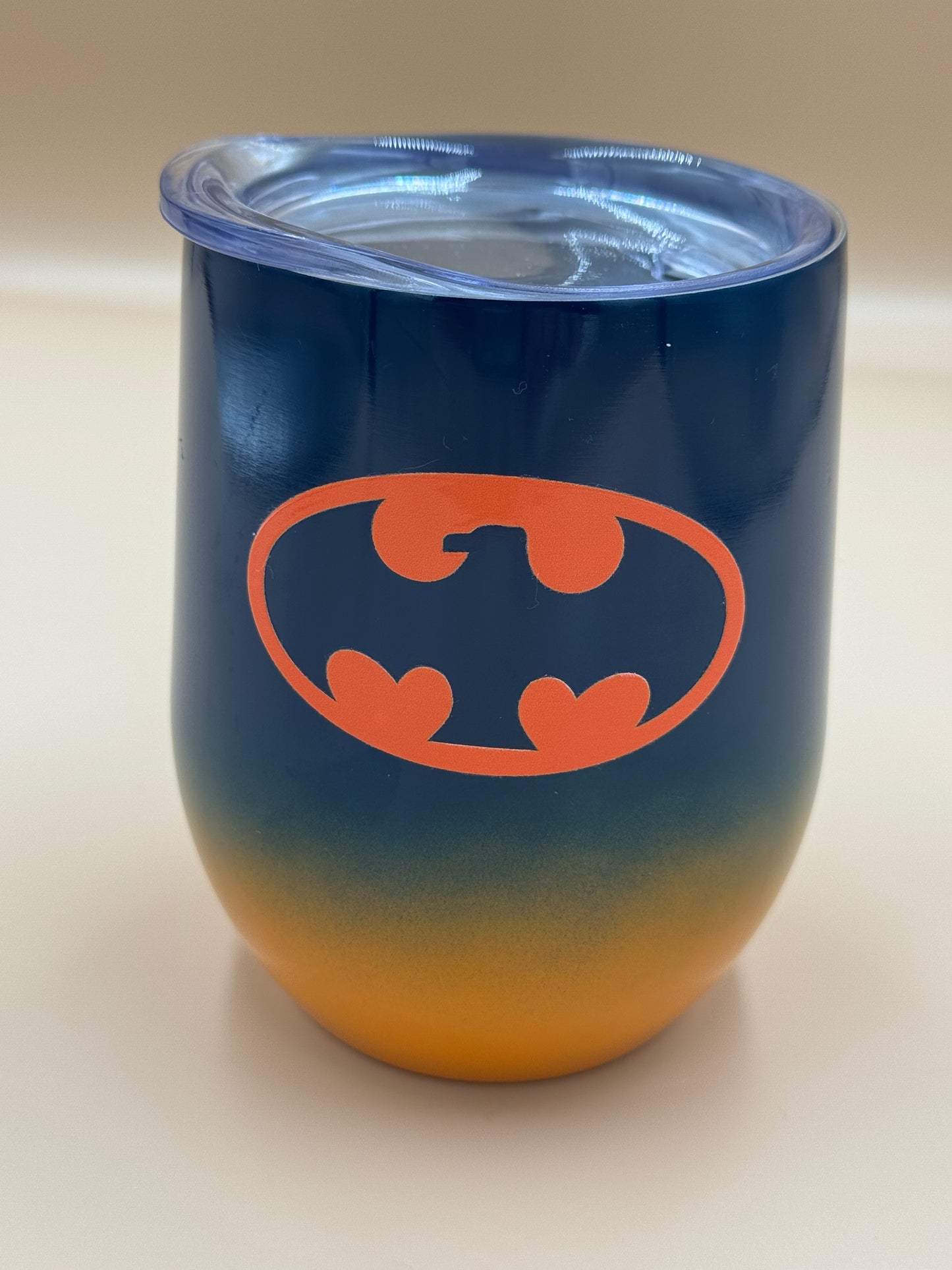 Blue and orange tumbler with orange bat symbol on a beige background