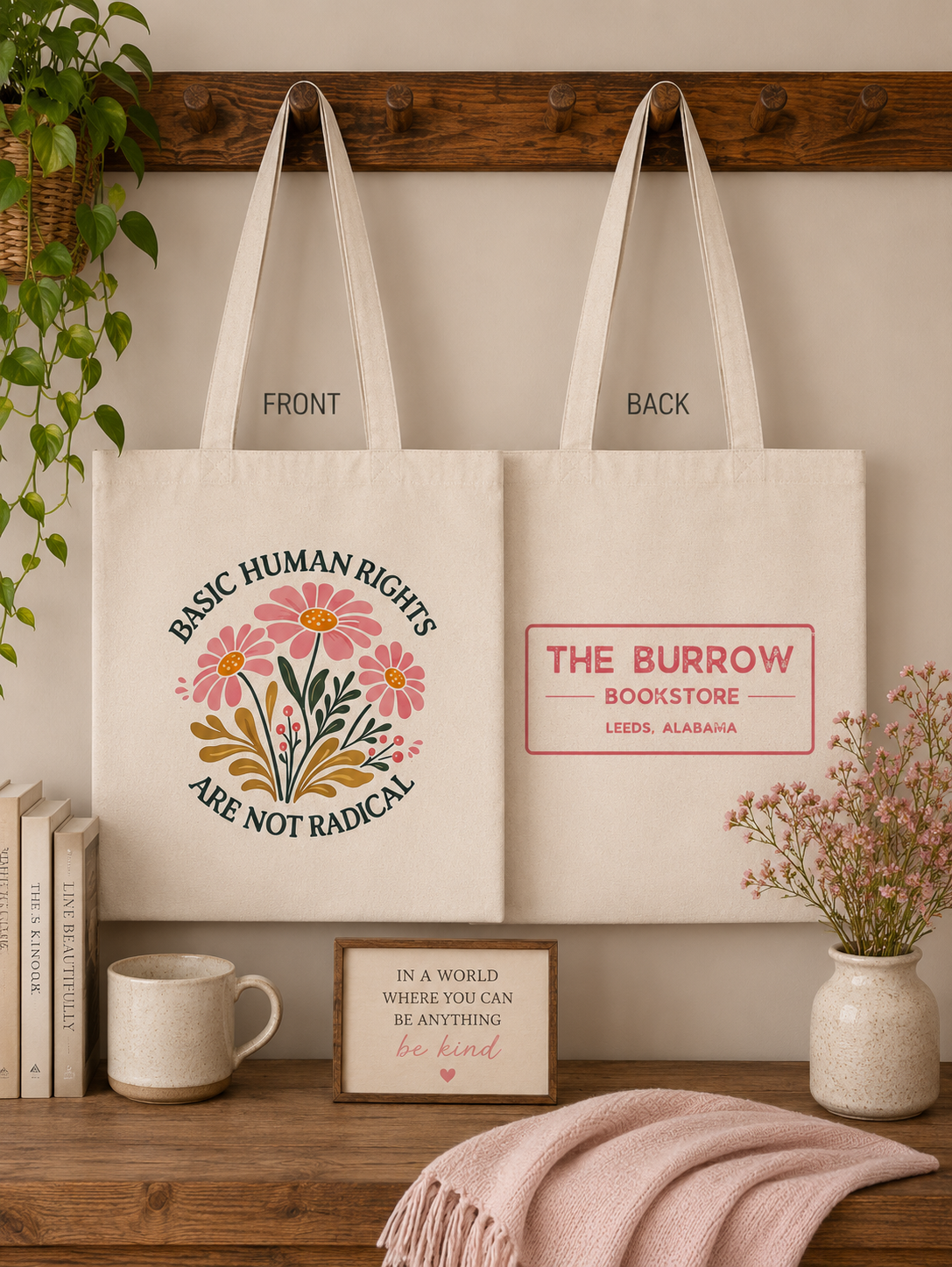 Natural canvas two-sided tote bag featuring a Basic Human Rights Are Not Radical floral design on the front and The Burrow Bookstore logo on the back.