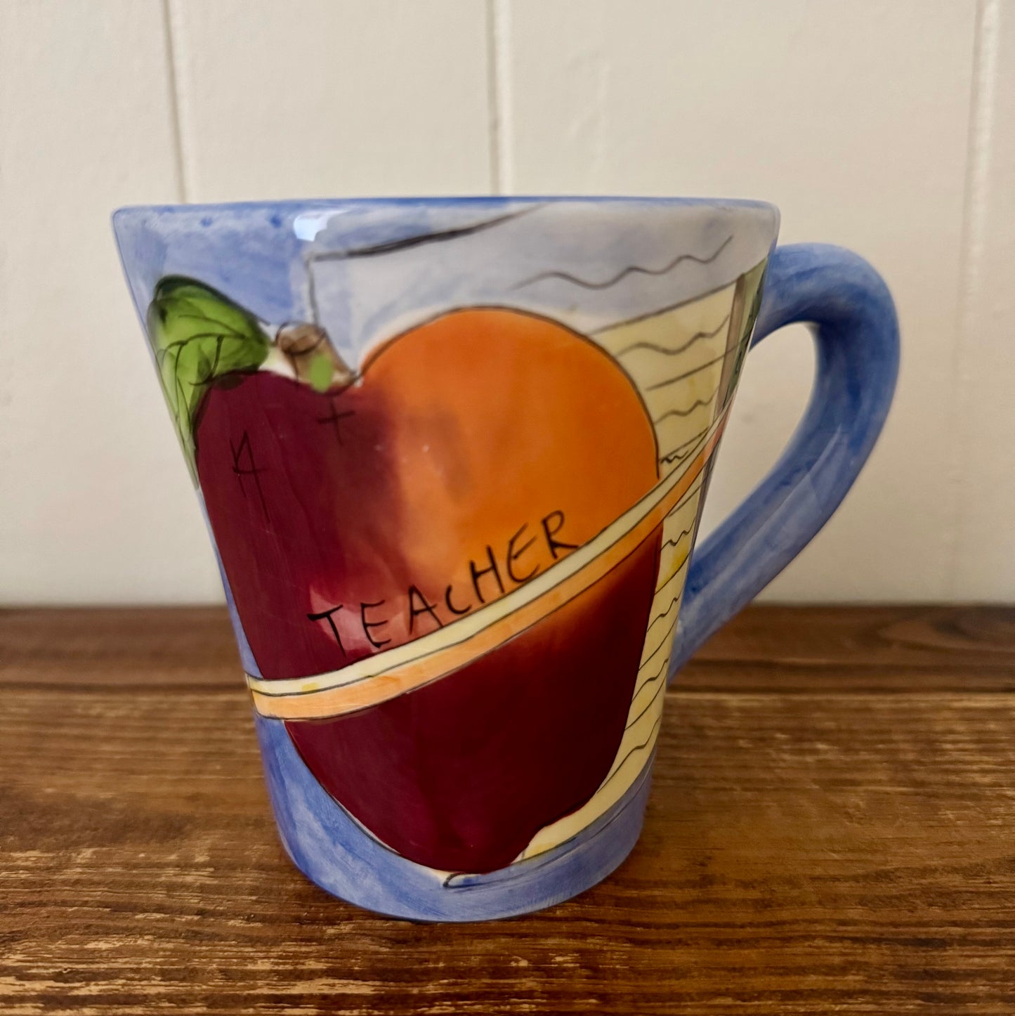 Mug with a painted apple and 'Teacher' text on a wooden surface