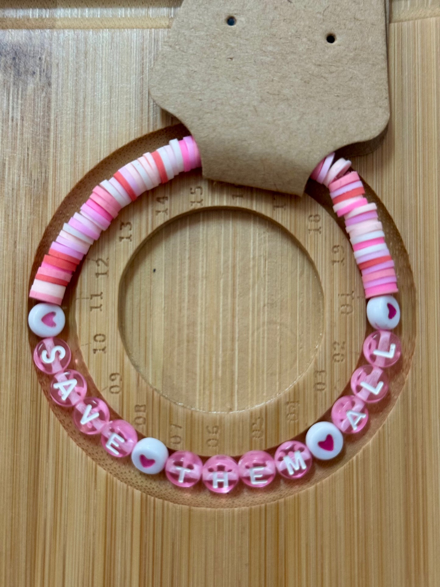 Pink beaded bracelet with letter beads on a wooden surface