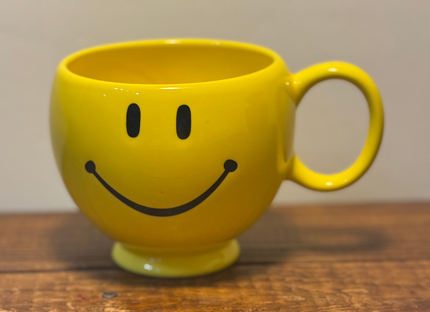 Large yellow mug with a smiley face on the front and a retro 1950s housewife on the back, saying Tell me to smile one more time.