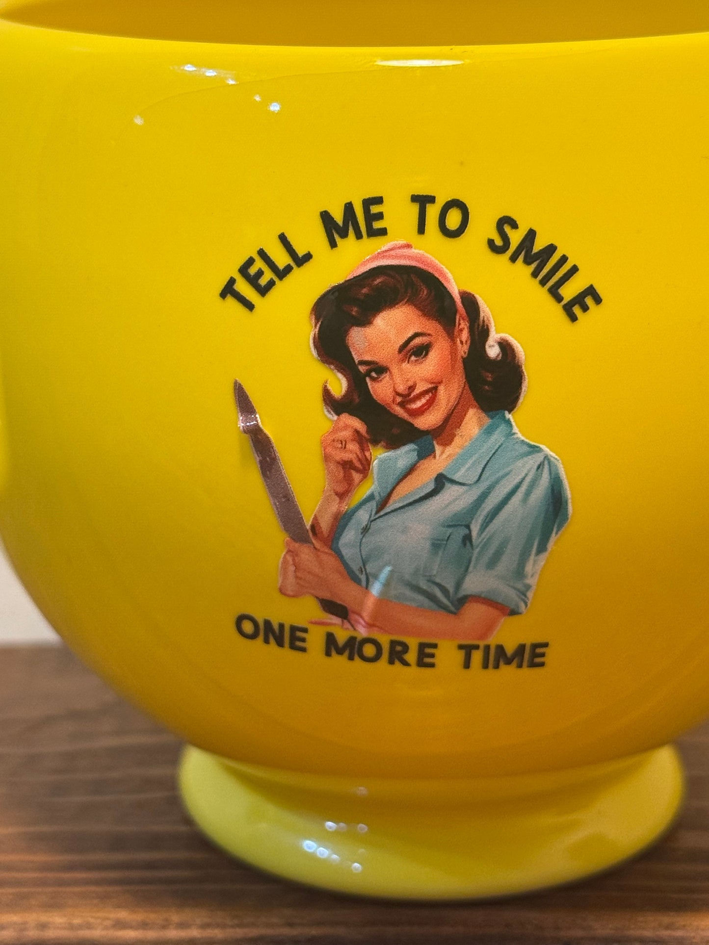 Large yellow mug with a smiley face on the front and a retro 1950s housewife on the back, saying Tell me to smile one more time.