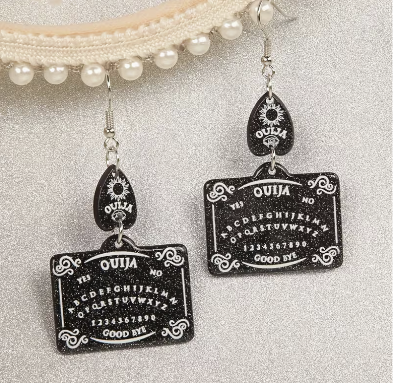 Black glitter Ouija board dangle earrings with white spirit board lettering, decorative planchette accents and silver-tone hooks