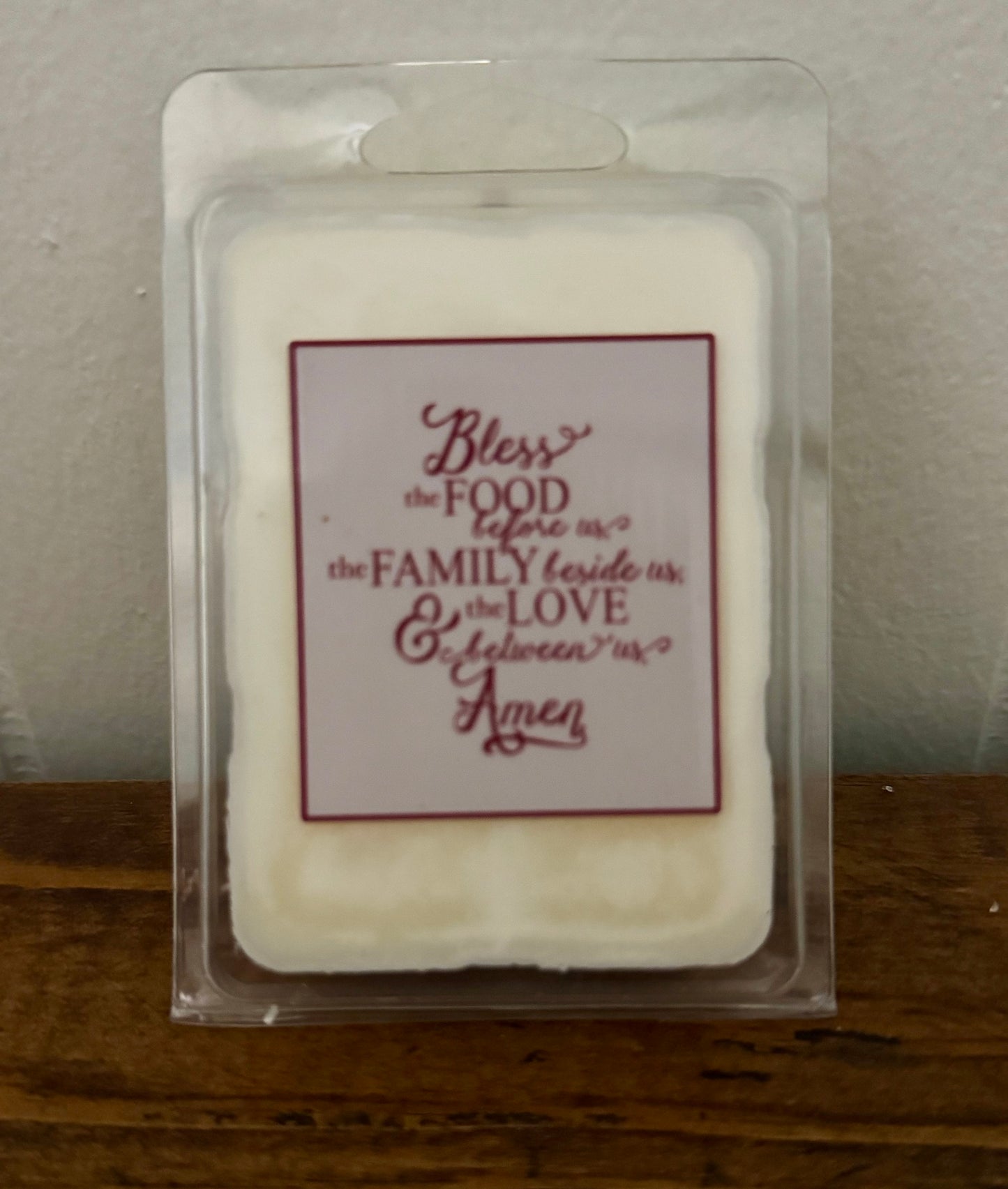 Packaged wax melt with a religious quote on a wooden surface