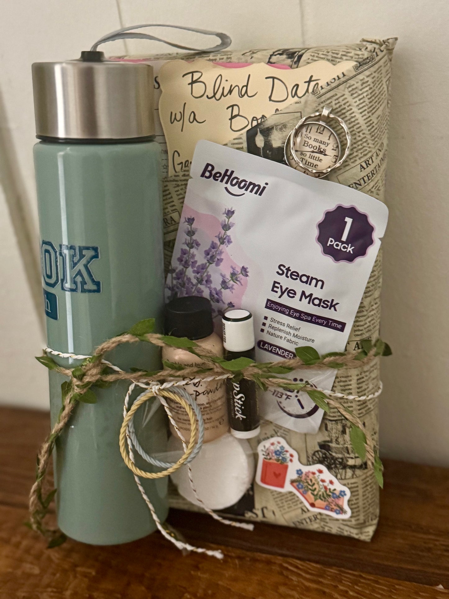 Gift basket with items including a water bottle, eye mask, and small bottles on a wooden surface.