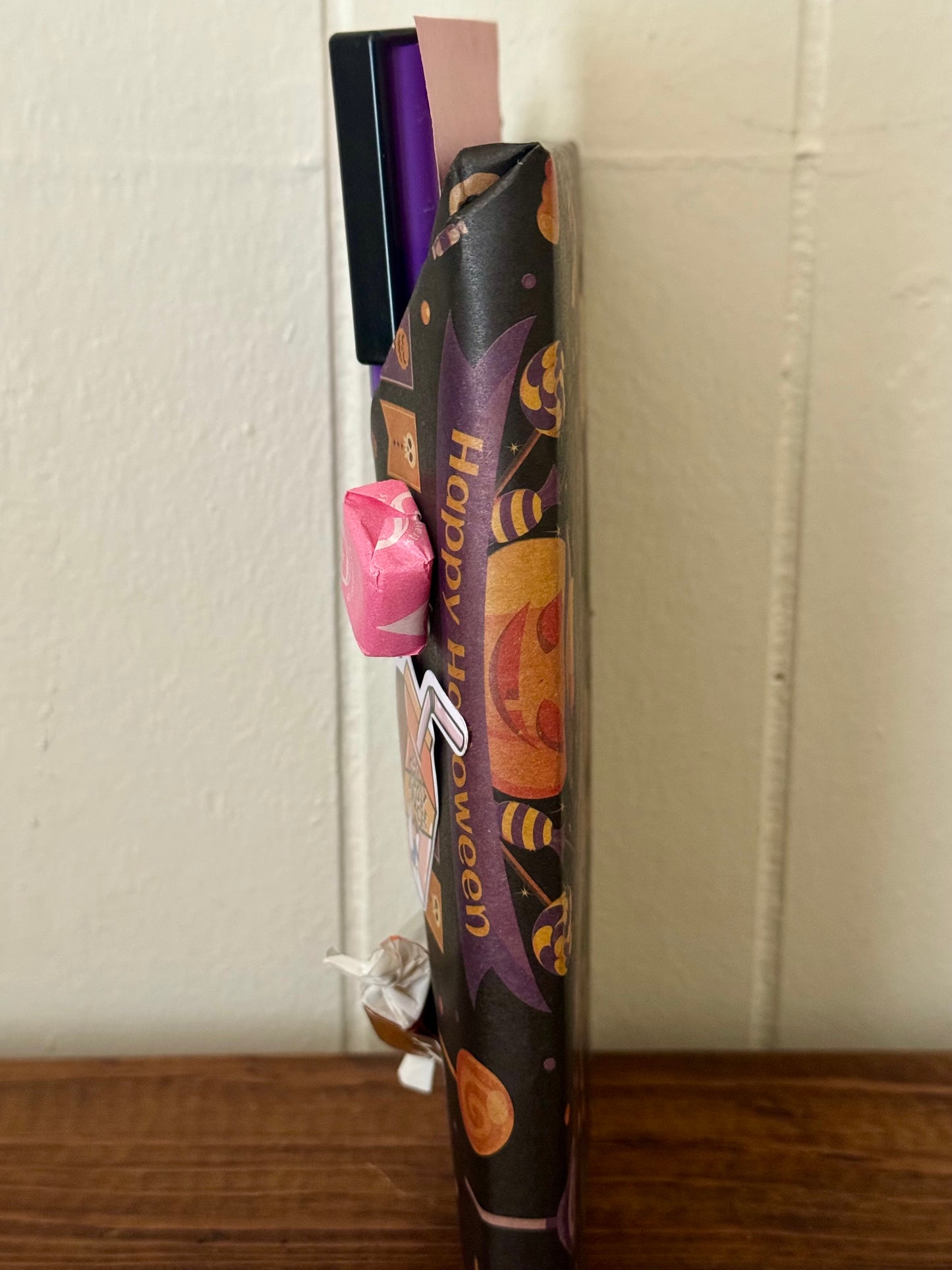 Halloween-themed candy bag with a pink candy on a textured surface