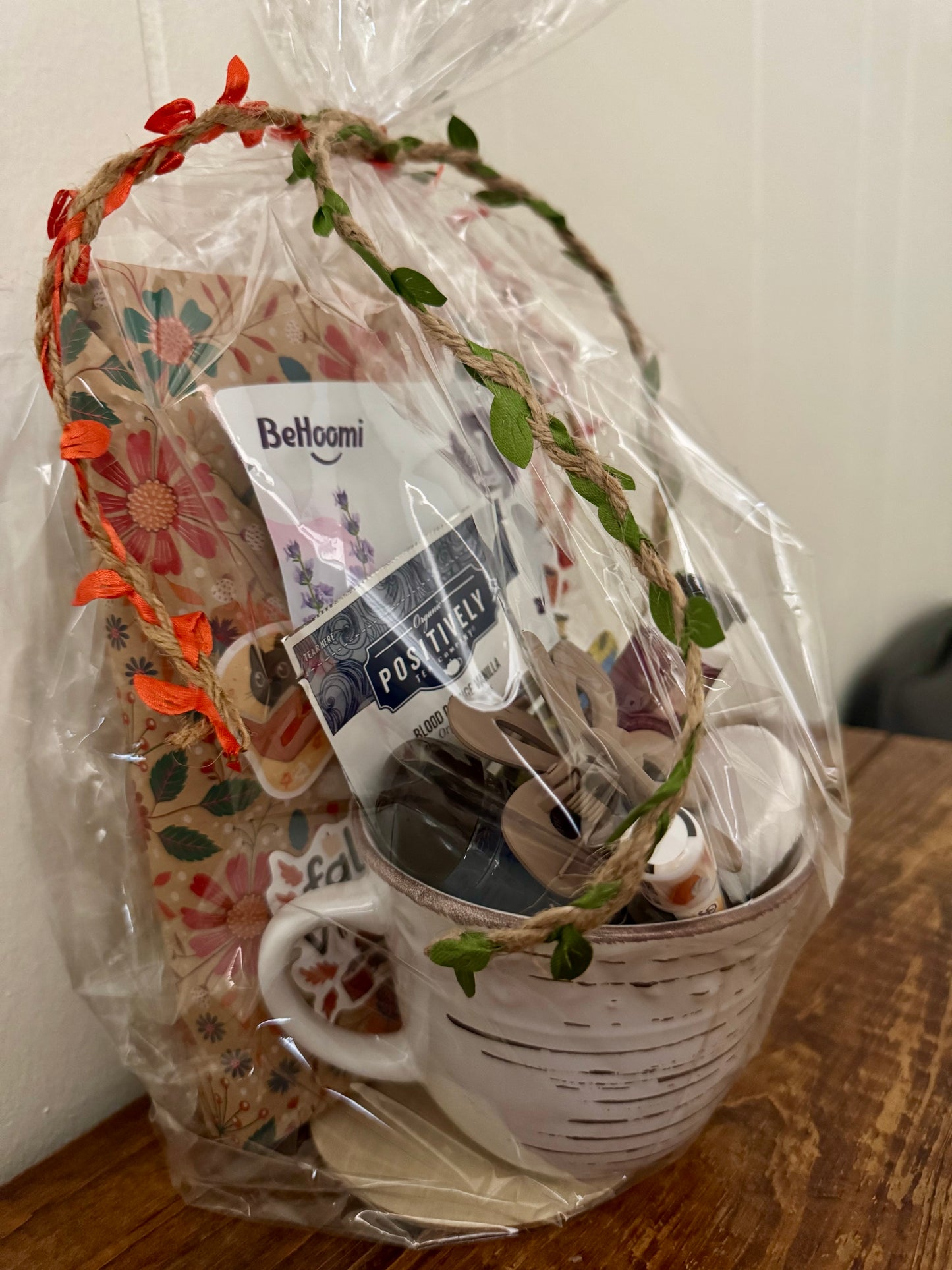 Gift basket with a mug, decorative items, and a Bellemi product on a wooden surface.