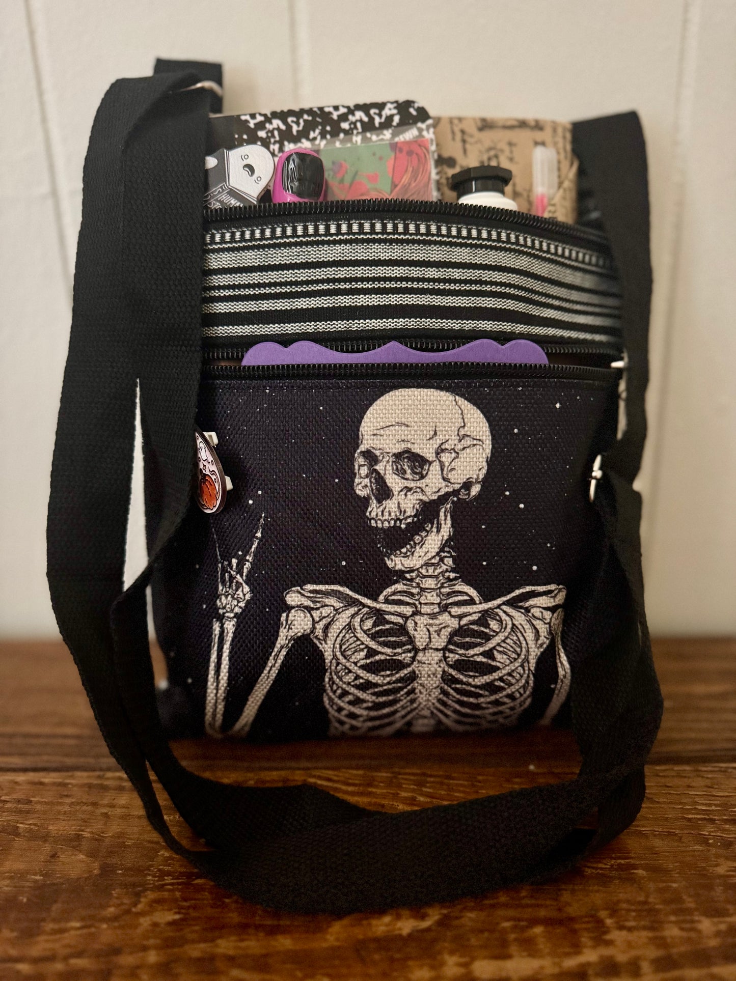 Black crossbody bag with skeleton design on a wooden surface