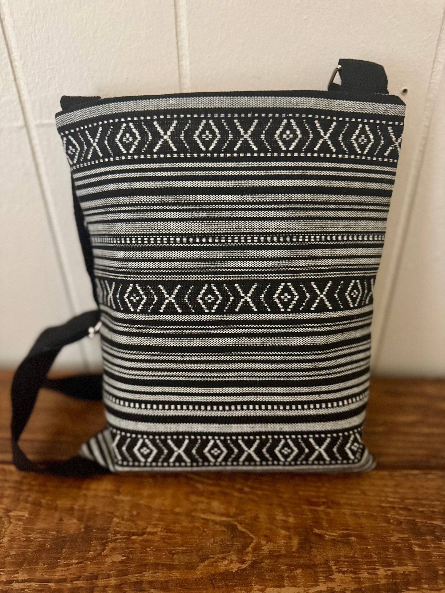 Black and white patterned bag on a wooden surface with a white wall background