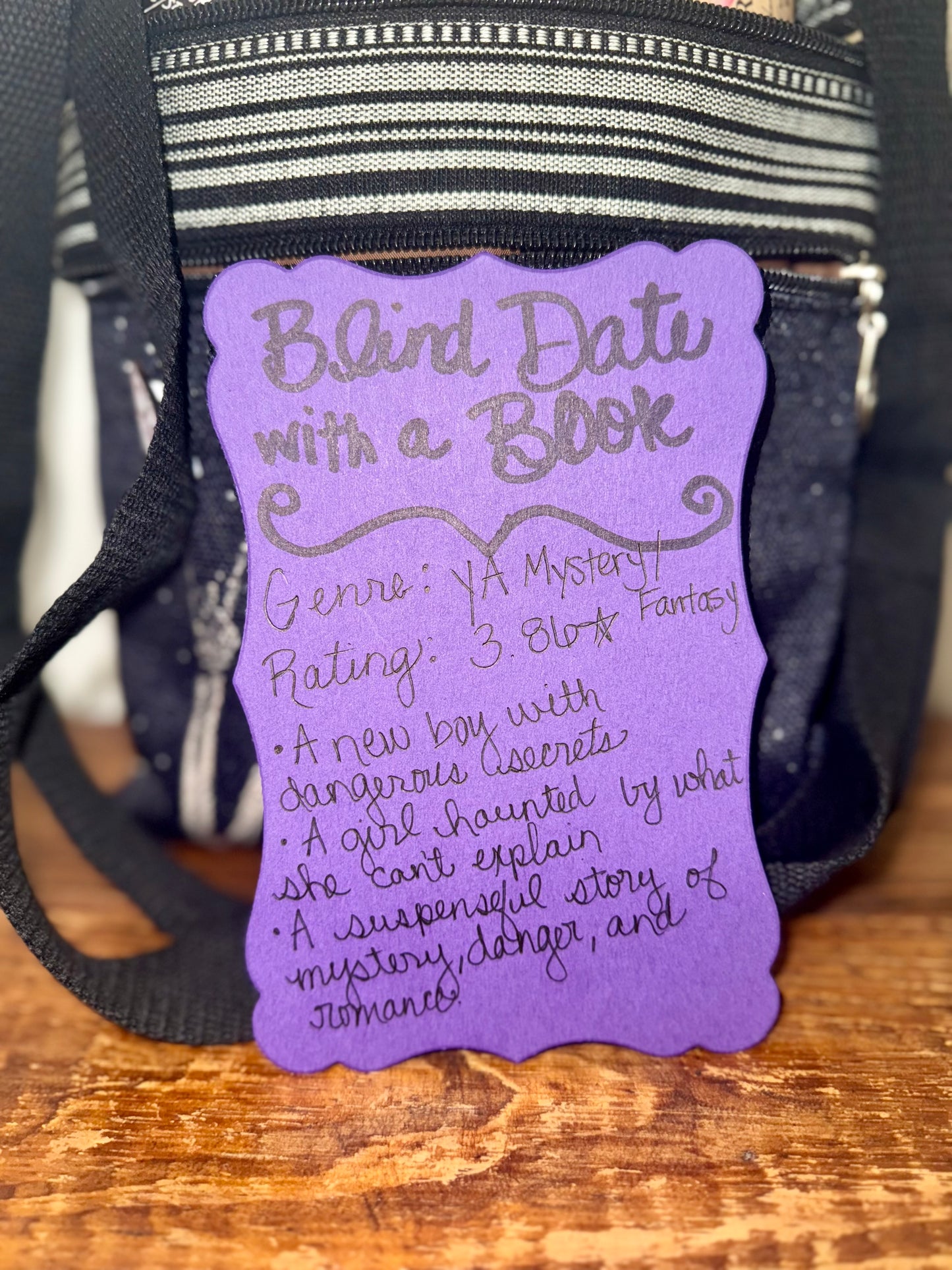 Purple book tag with text on a black bag