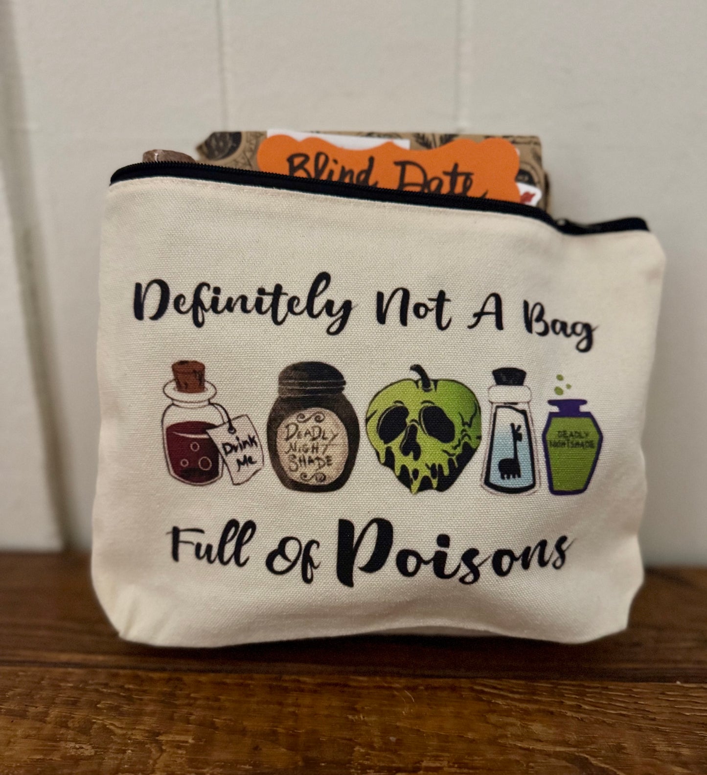 Canvas pouch with poison-themed illustrations and text on a wooden surface.