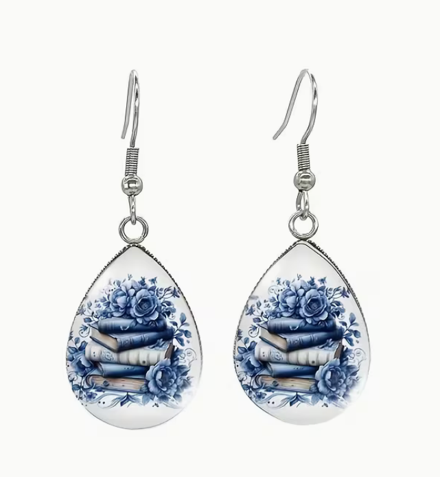Teardrop dangle earrings featuring blue floral artwork surrounding a stack of books in a silver-tone setting.