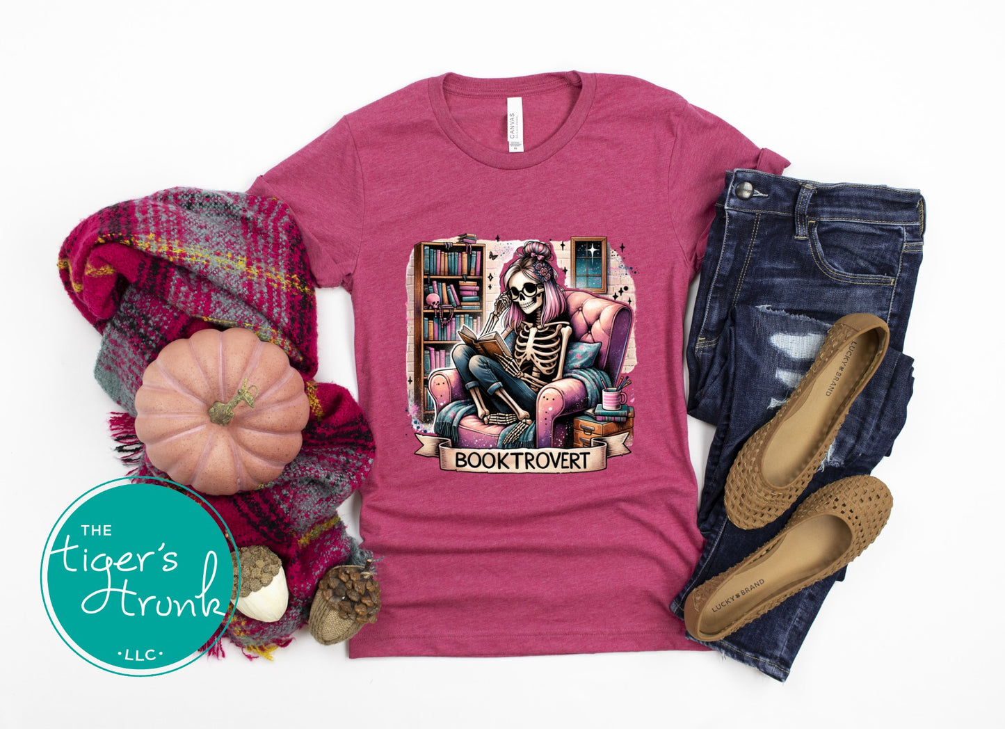 Pink t-shirt with skeleton graphic and 'Booktrovert' text, surrounded by autumn-themed items.