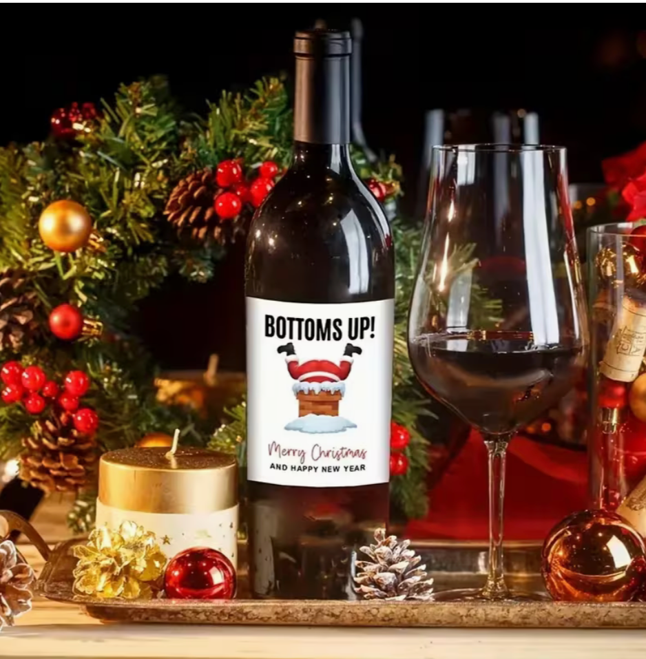 Festive Christmas wine bottle label with glittery upside down design featuring Christmas boots and snowflakes, displayed on a holiday themed background
