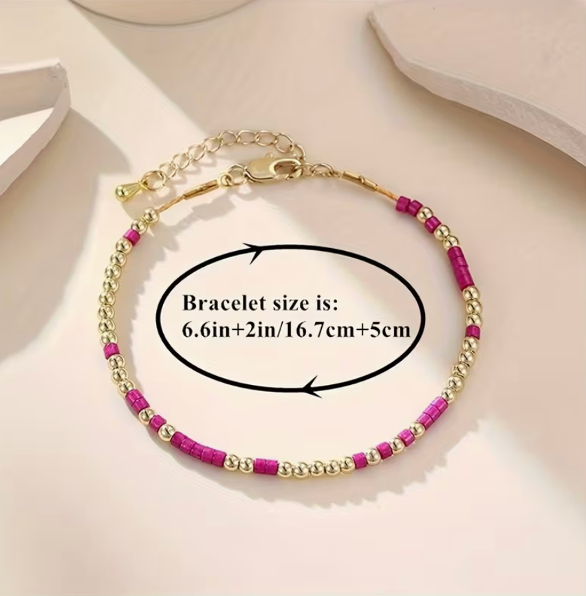 Bracelet with gold and pink beads on a light background