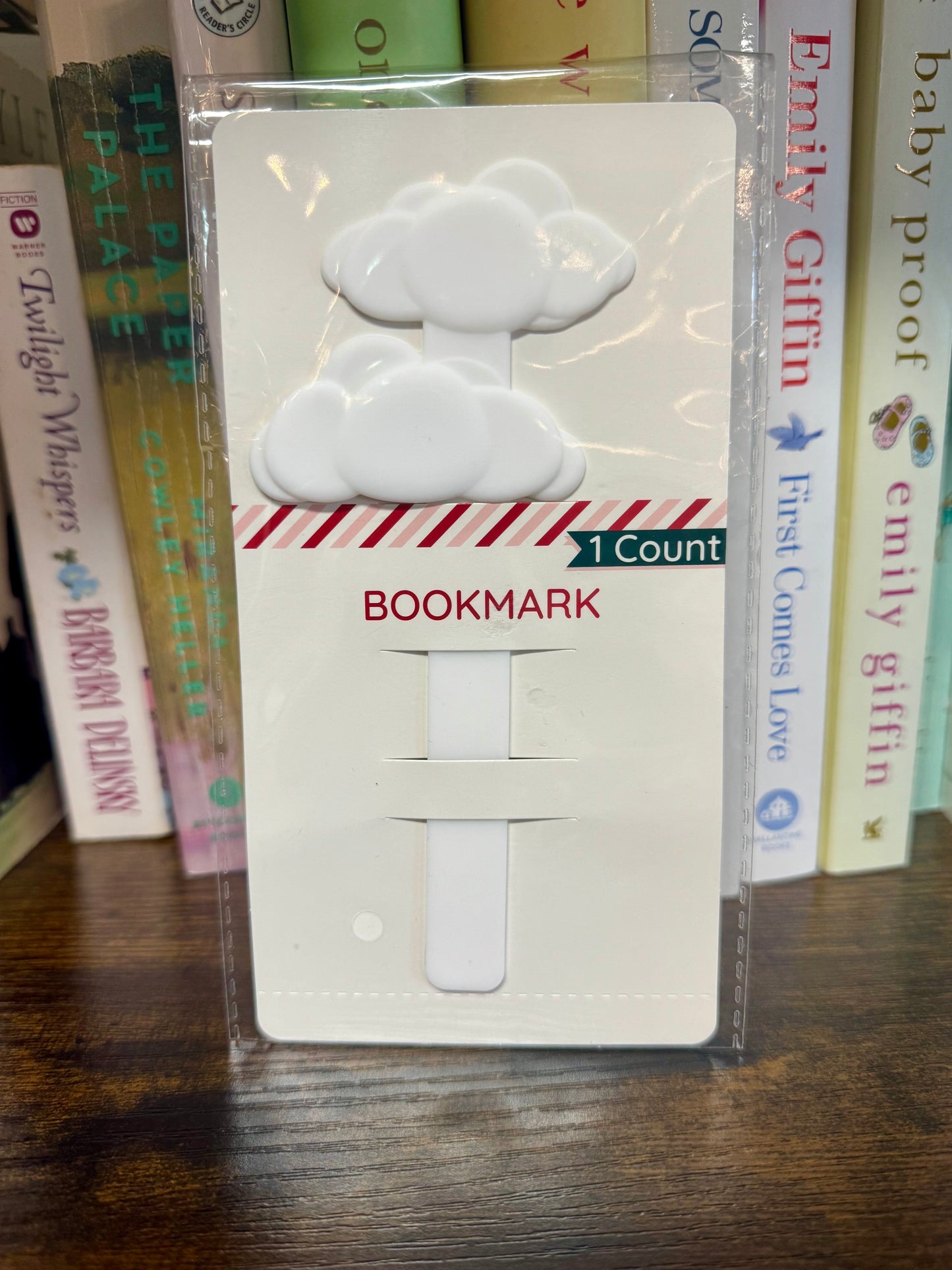 White cloud-shaped bookmark in packaging with books in the background