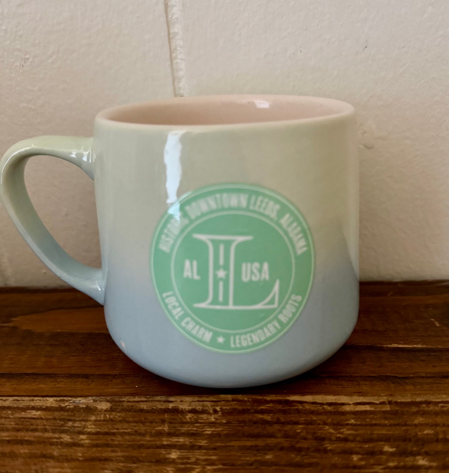 White mug with green logo on a wooden surface