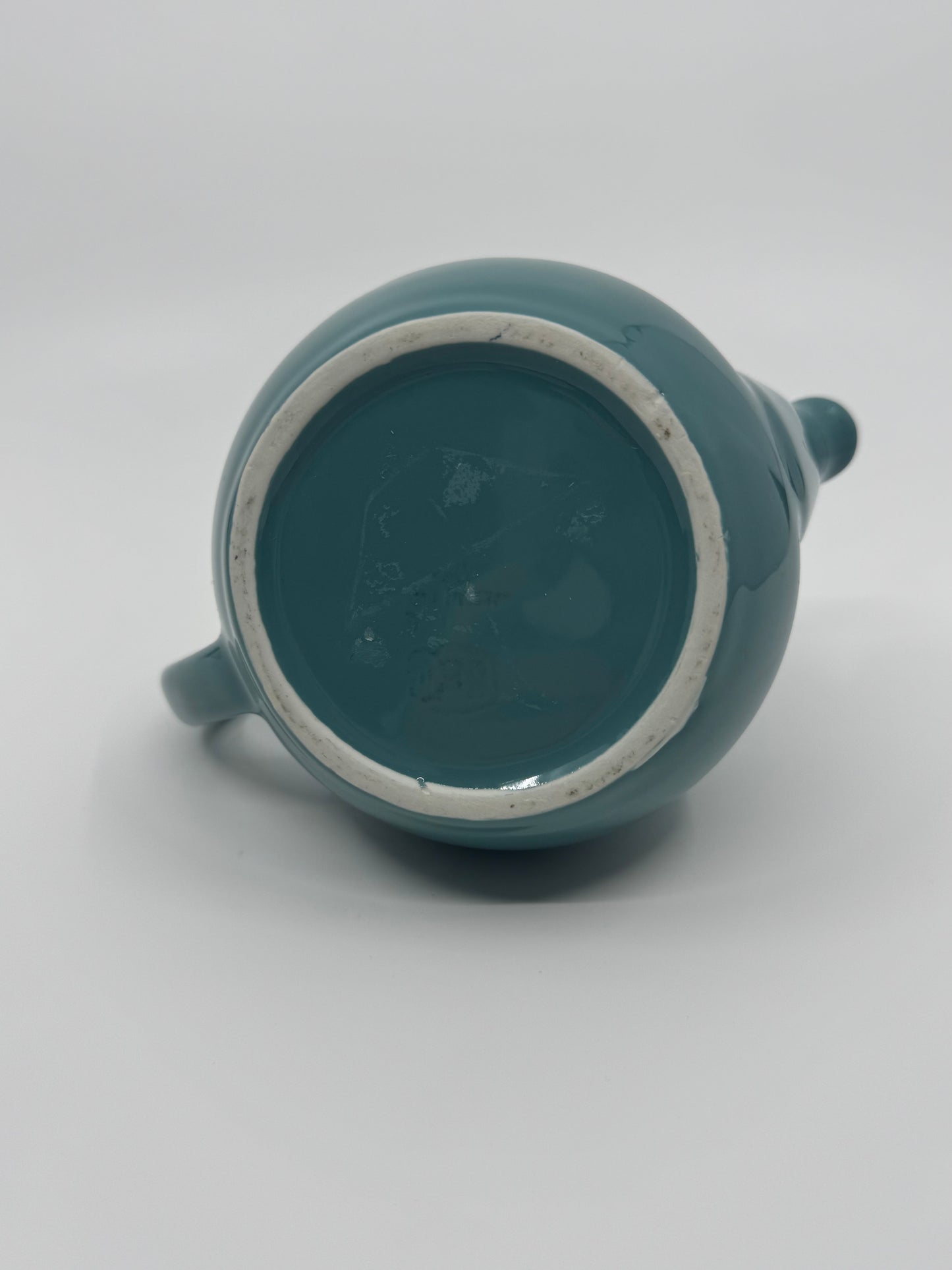 Teal ceramic teapot on a light gray background