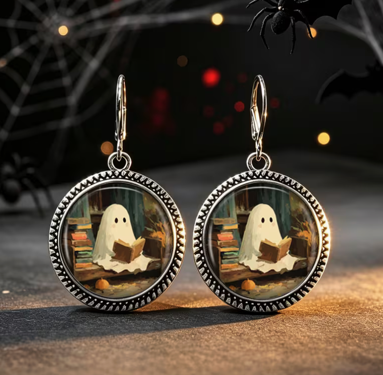 Antique silver-tone round dangle earrings featuring an adorable ghost reading a book beside stacks of books in a cozy spooky library scene