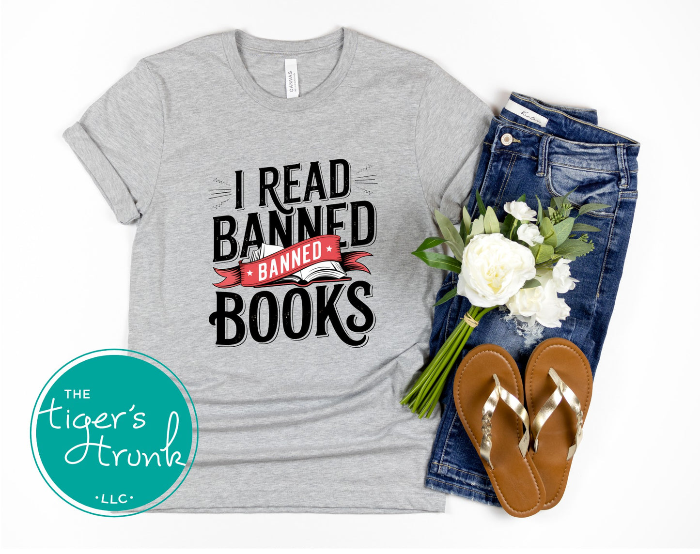 Gray t-shirt with 'I Read Banned Books' text, jeans, sandals, and flowers on a white background.