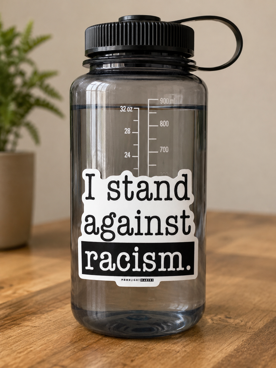 Black and white I Stand Against Racism vinyl sticker displayed on a reusable water bottle.