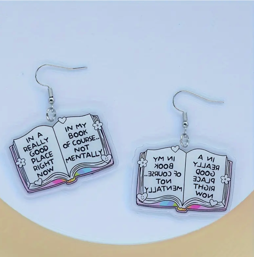 Acrylic dangle earrings shaped like open books—one page reads In a Really Good Place Right Now, the other In My Book of Course… Not Mentally, with stainless steel hooks.