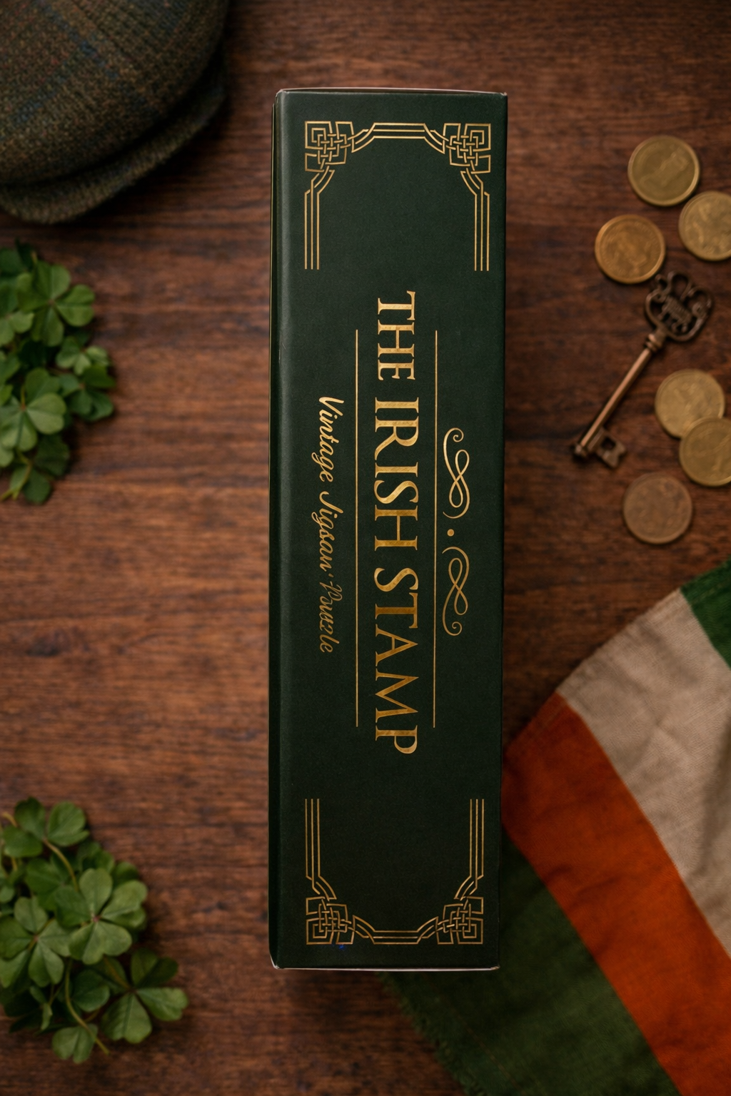 Side view of The Irish Stamp vintage jigsaw puzzle box in deep green with gold lettering on a wooden table styled with shamrocks, coins, and an Irish flag.
