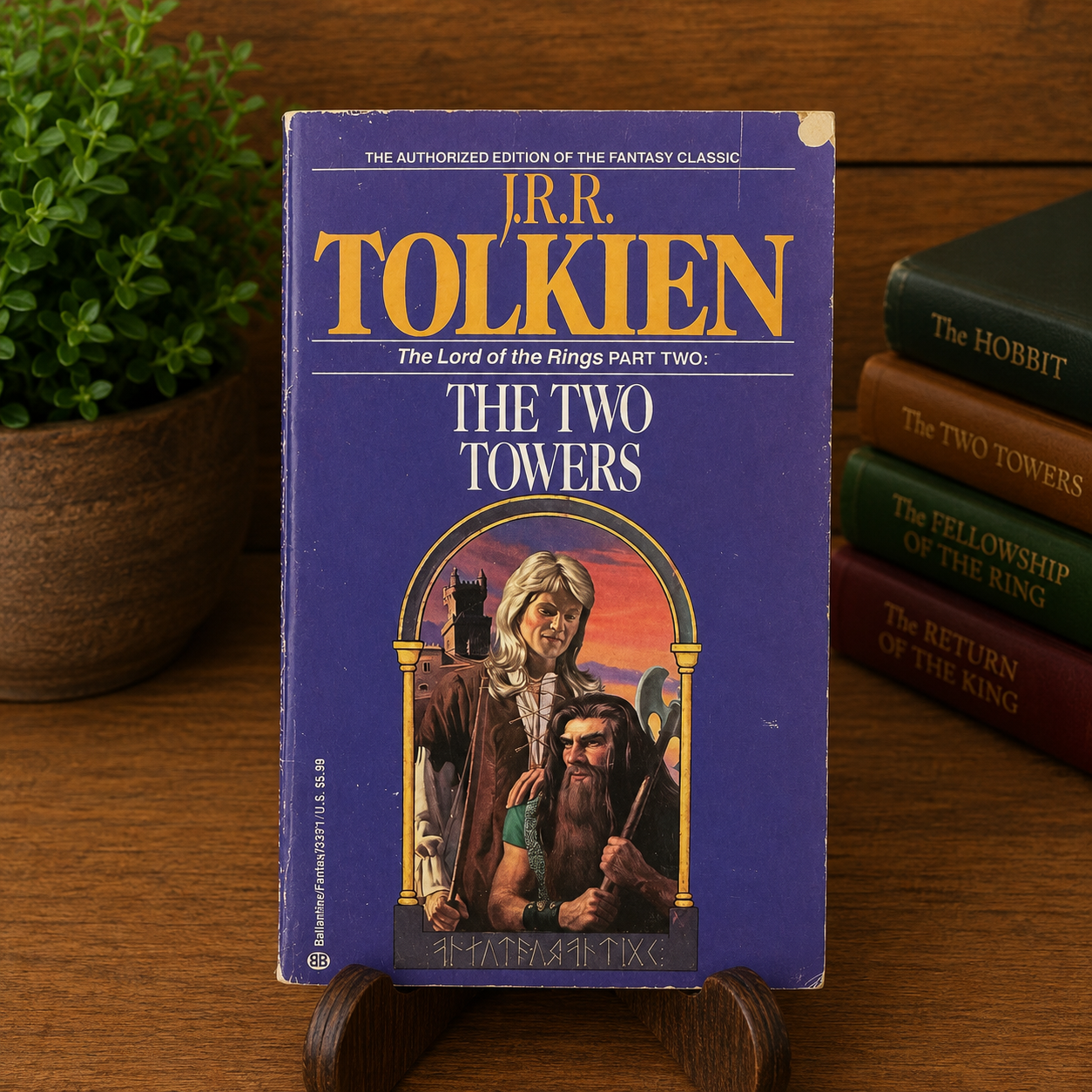 Vintage The Two Towers by J.R.R. Tolkien, Ballantine Books paperback, displayed upright on a wooden stand with a warm bookshelf background. The purple front cover retains its authentic fair-condition wear, including edge wear, corner rubbing, light surface scuffs, and a small circular hole punch near the upper-right corner.