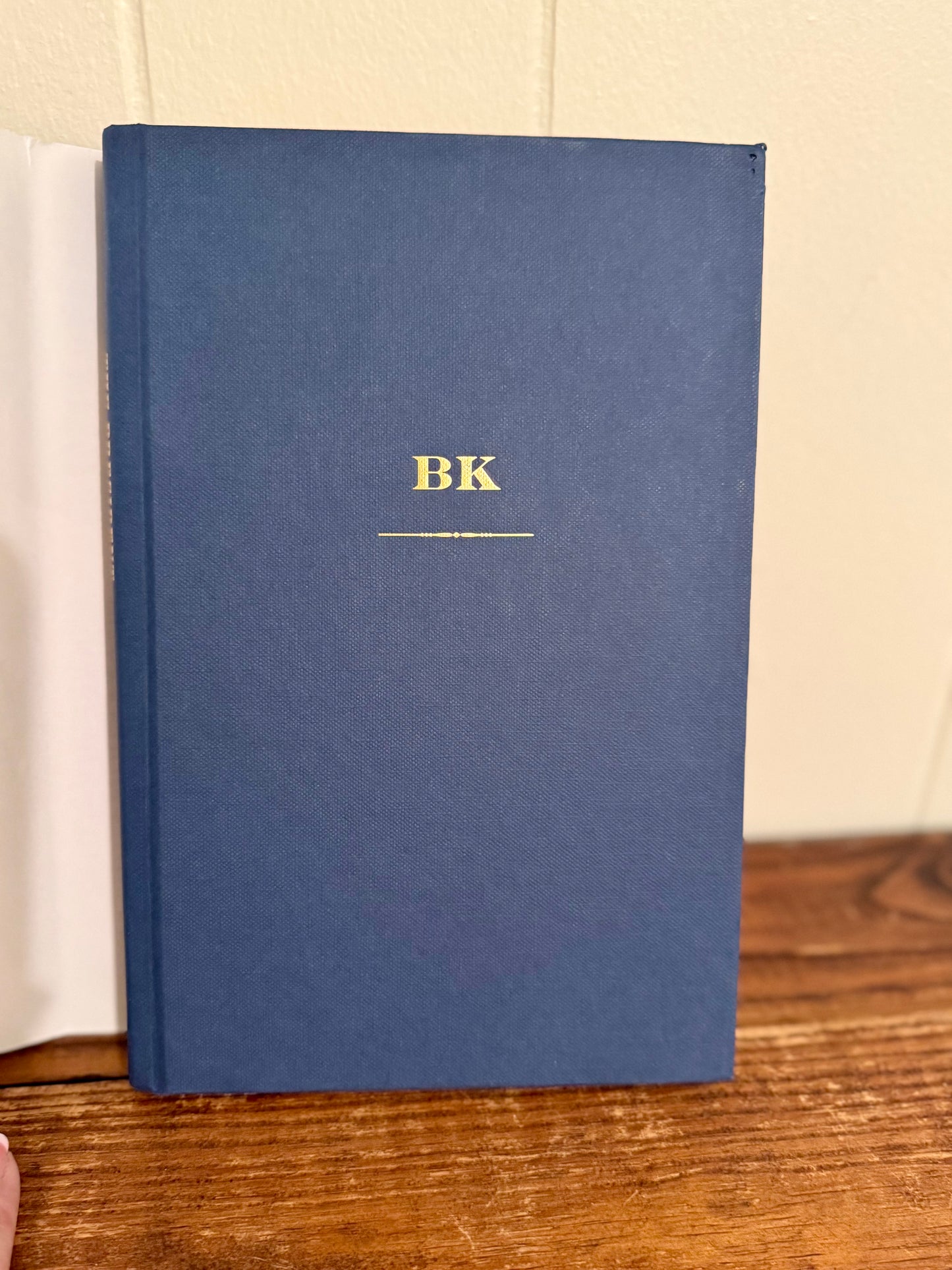 Blue book with 'BK' on a wooden surface