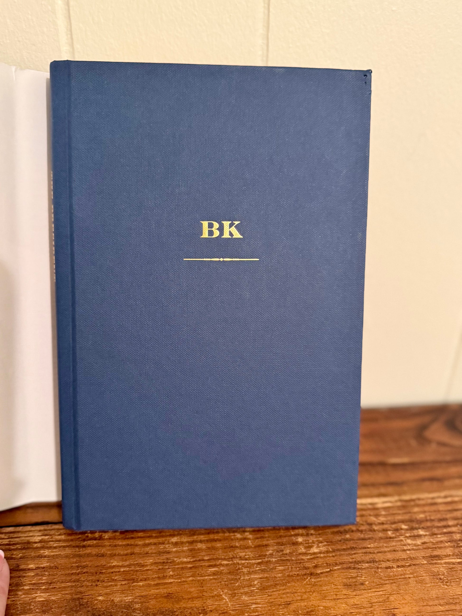 Blue book with 'BK' on a wooden surface