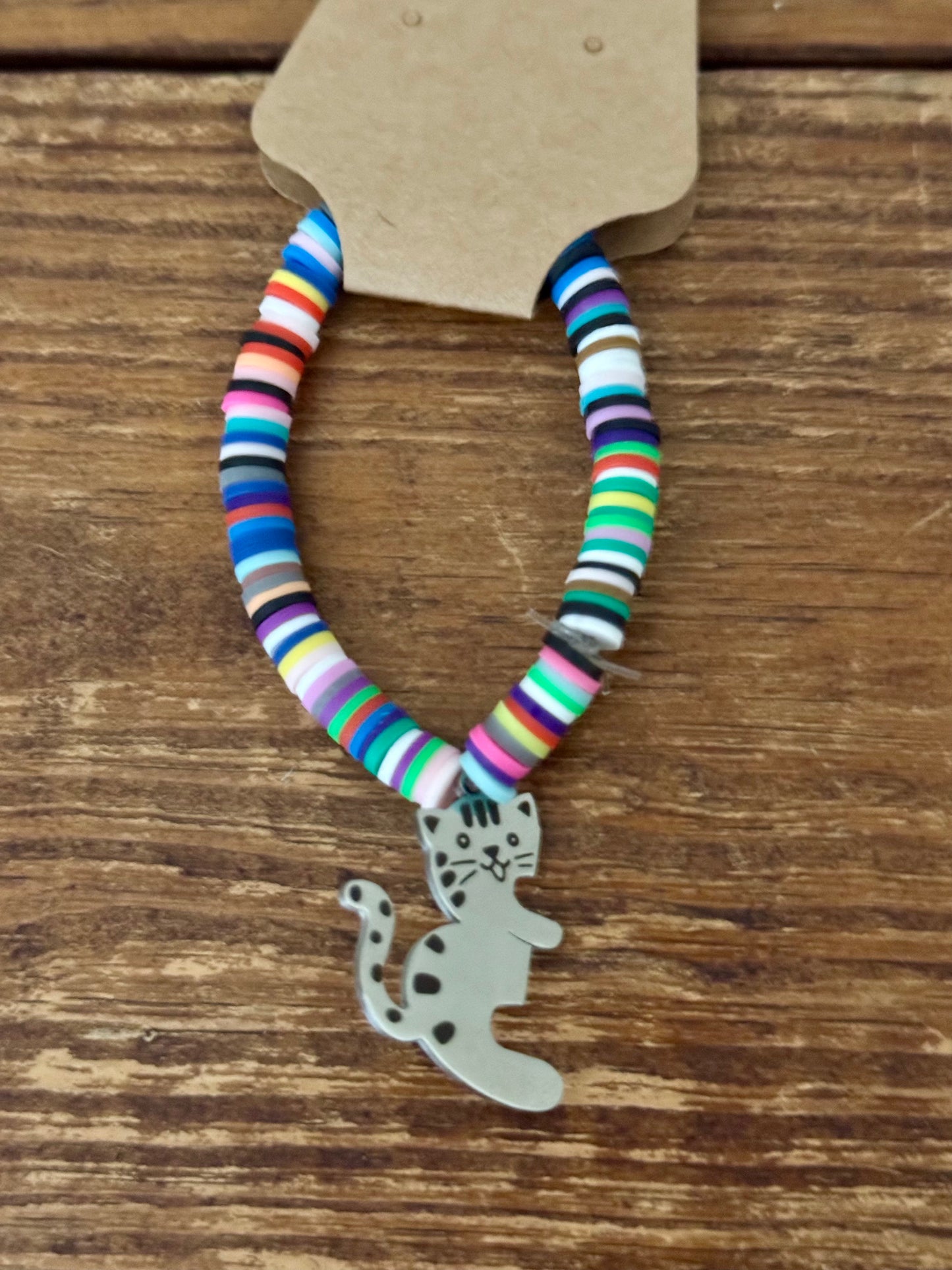 Colorful beaded bracelet with a cat charm on a wooden surface