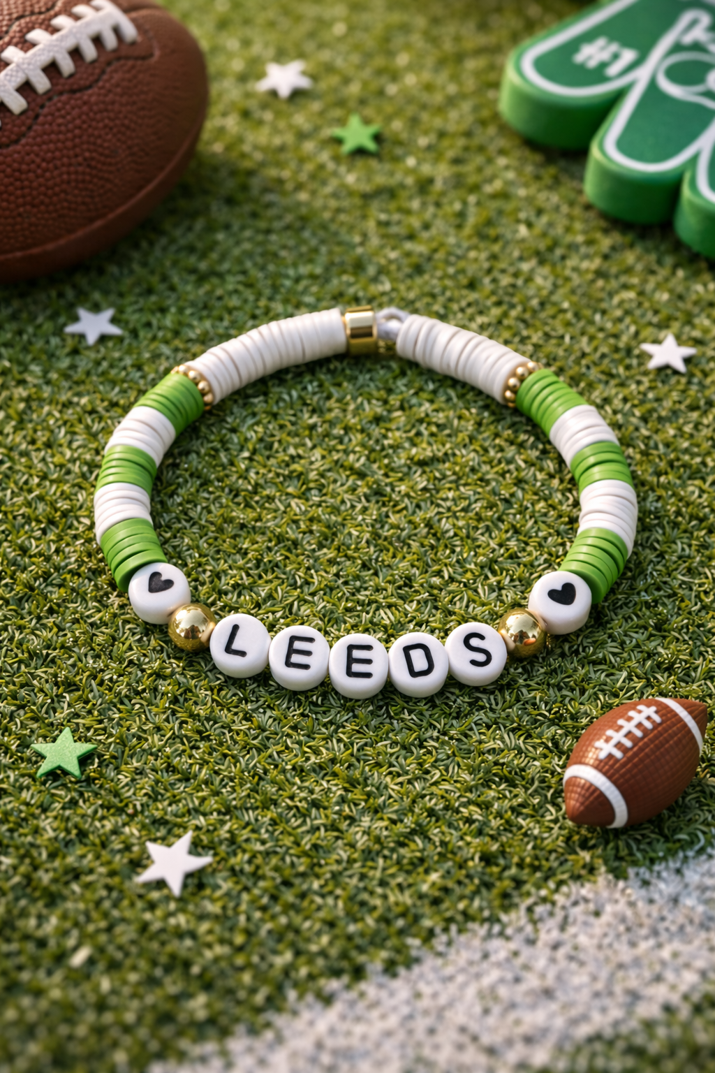 Bracelet with 'LEEDS' beads on a grass-like surface with footballs and stars.