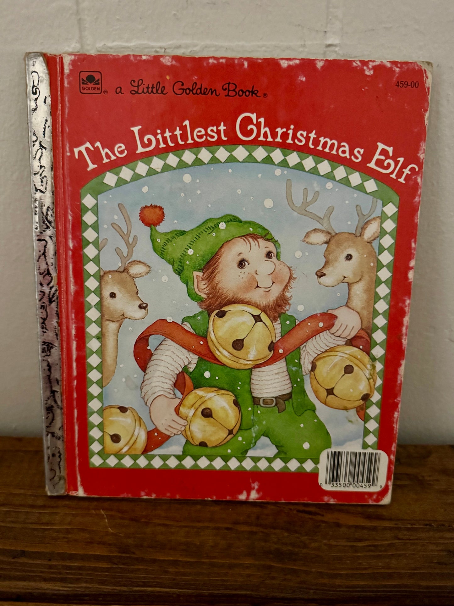 Vintage Little Golden Book titled The Littlest Christmas Elf with a red cover, foil spine, and an illustration of an elf holding jingle bells; fair+ condition.