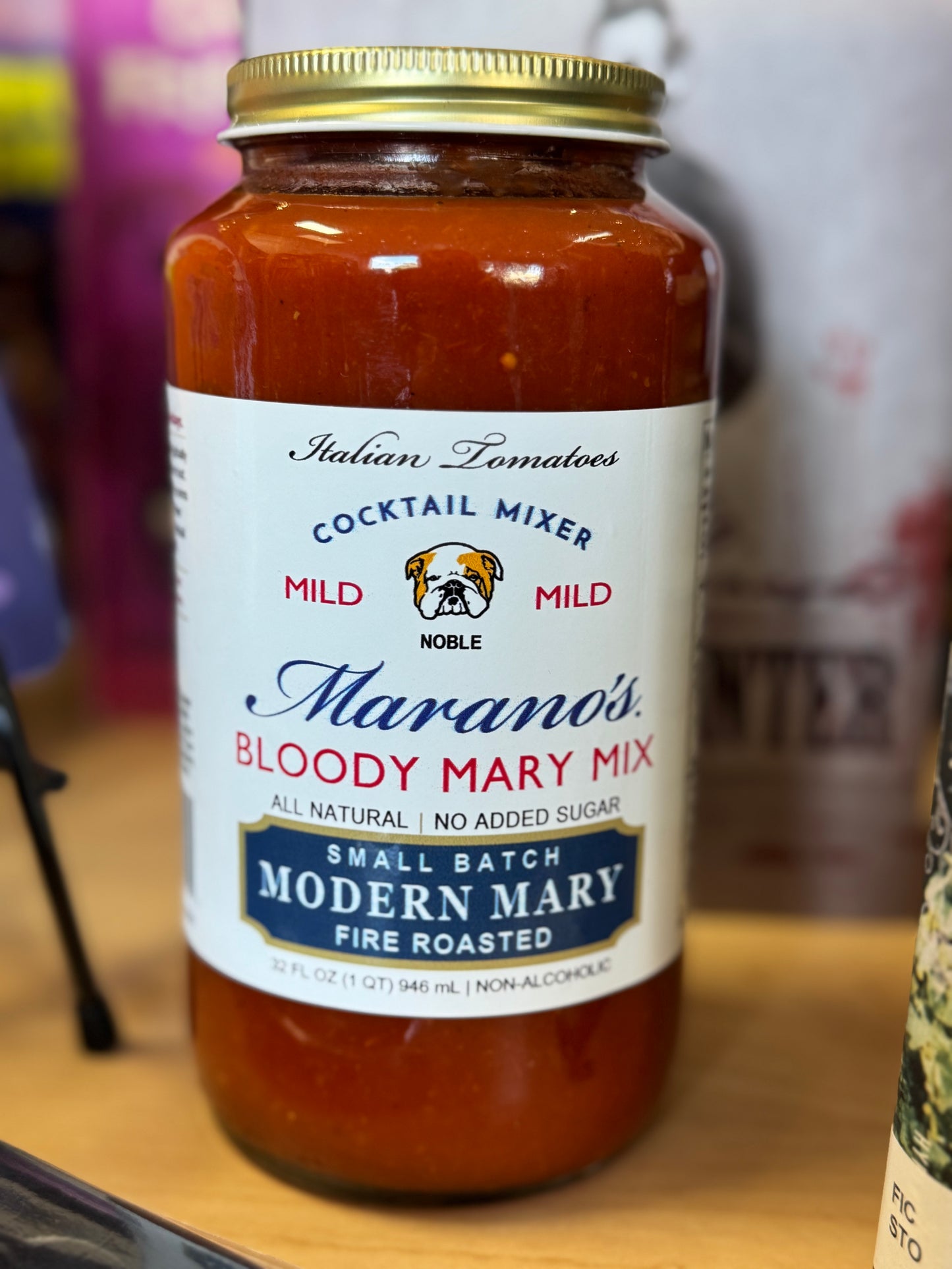 Jar of Marano's Bloody Mary Mix on a wooden surface with a blurred background