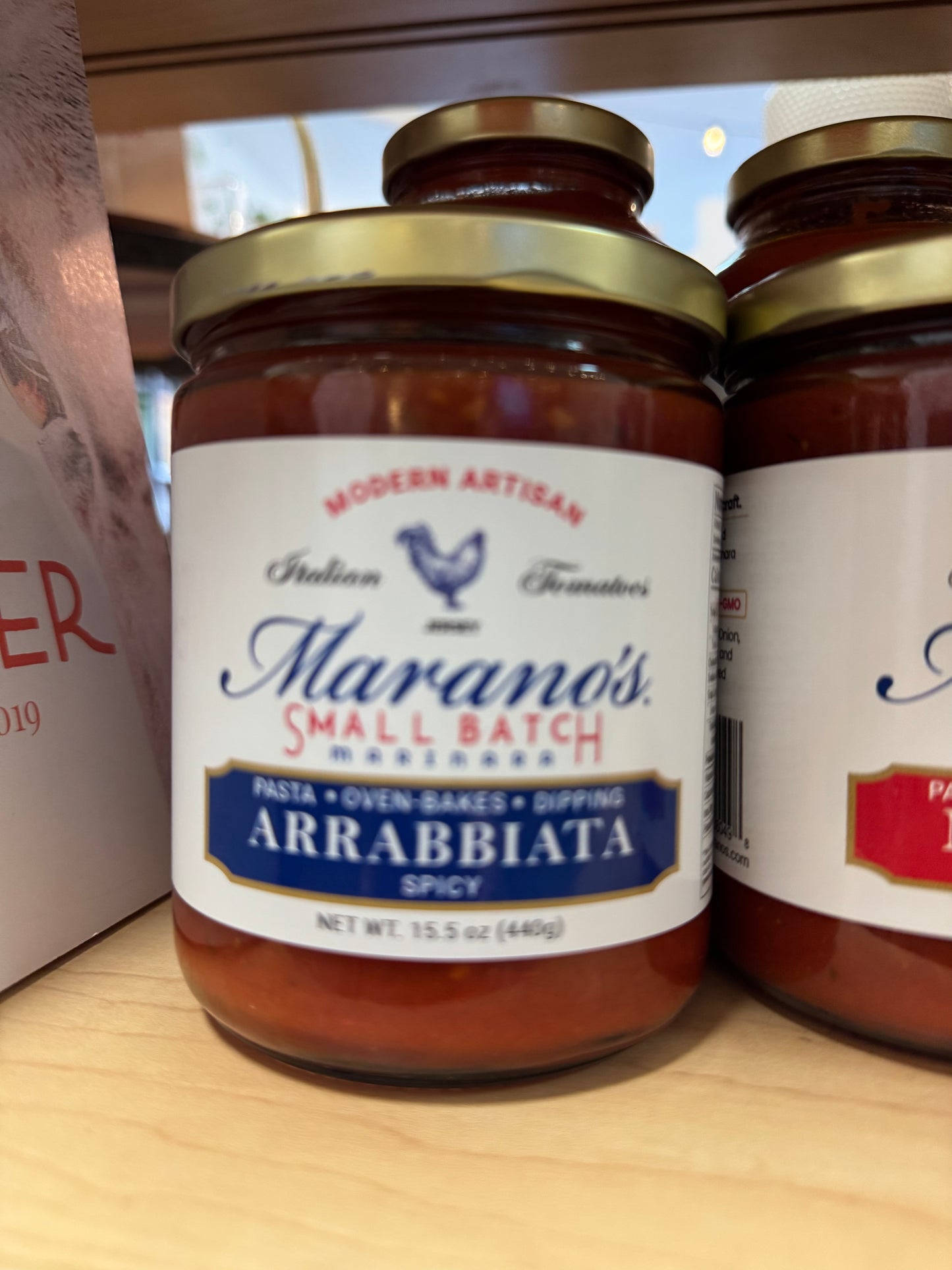 Jar of Marano's Small Batch Arrabbiata Spicy pasta sauce on a wooden surface.
