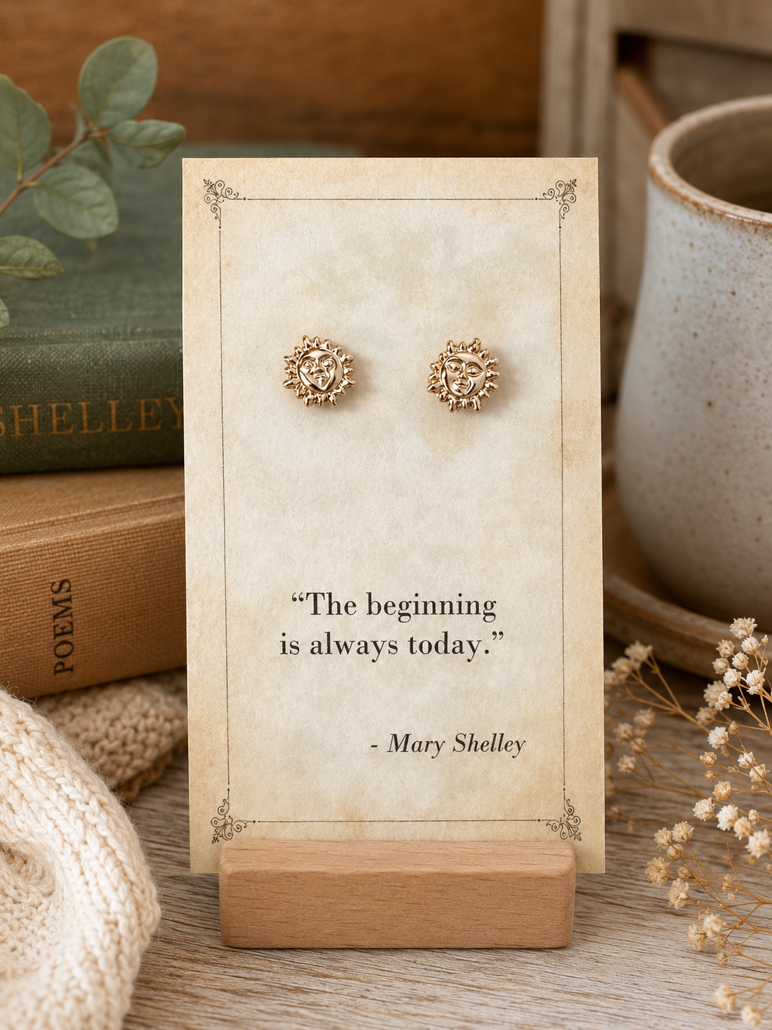 Gold tone sun and moon face stud earrings displayed on a vintage Mary Shelley literary quote card